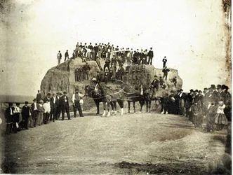 Una folla di uomini, bambini e pochi cavalli, si trova sopra e davanti al Grande Tumulo che è mostrato parzialmente livellato